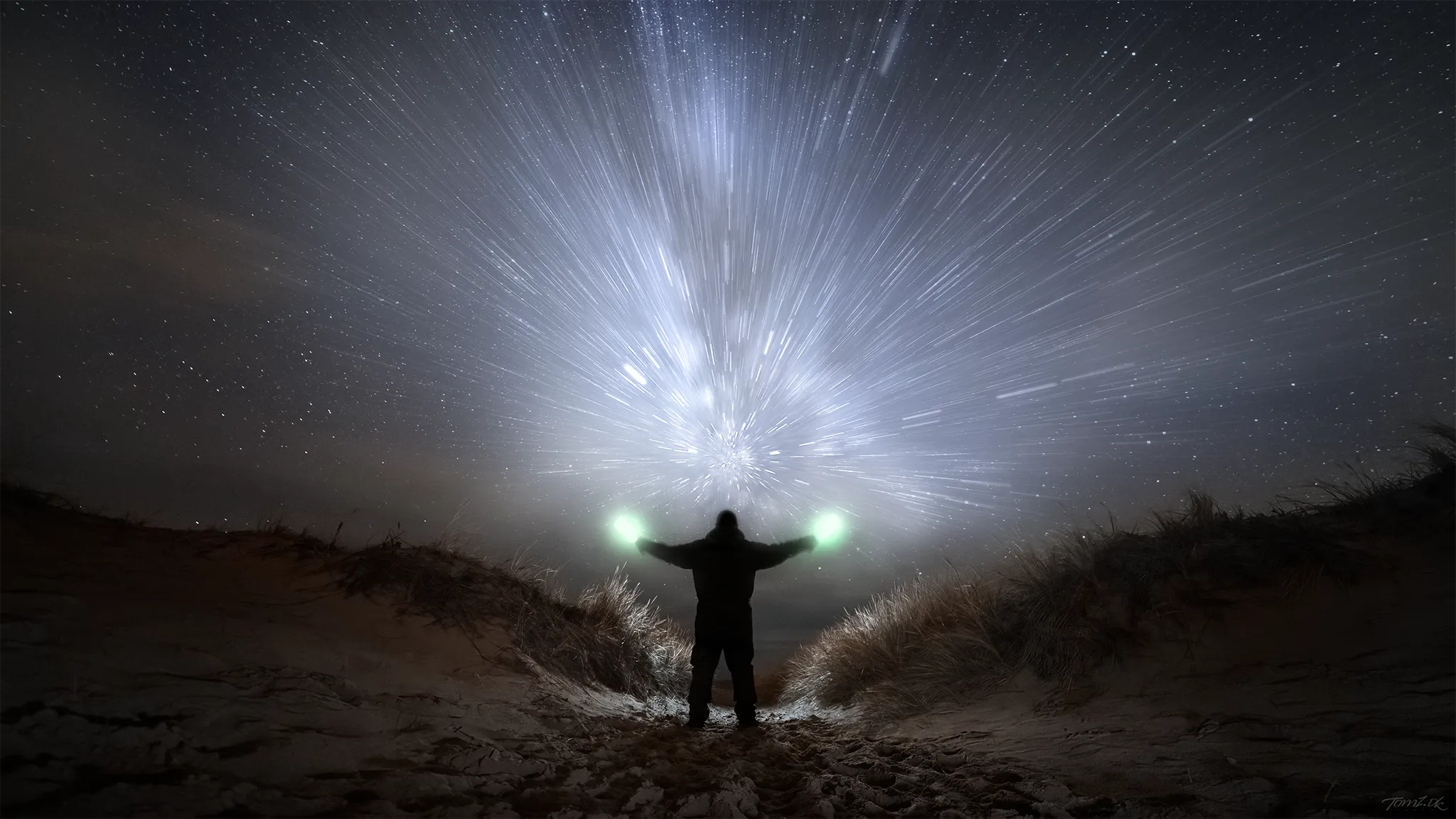 Fotograf ved stranden under Mælkevejen med korrekt manuel fokus på objektivet for skarpe stjerner og detaljeret astrofotografering.