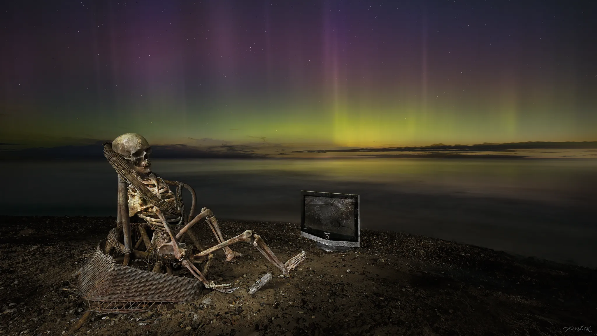 Skelet foran et TV på stranden under nordlys, som symboliserer overvågning af nordlysdata, Bz, IMF og solvind